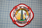 a fire department emblem with a red and white color scheme, including a sunburst design and a flag.