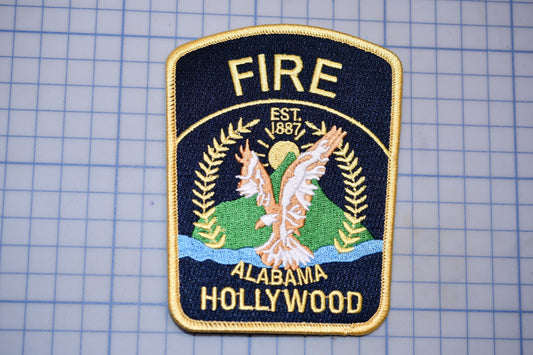 a fire department patch with the text "FIRE EST. 1987 ALABAMA HOLLYWOOD" and an eagle emblem.