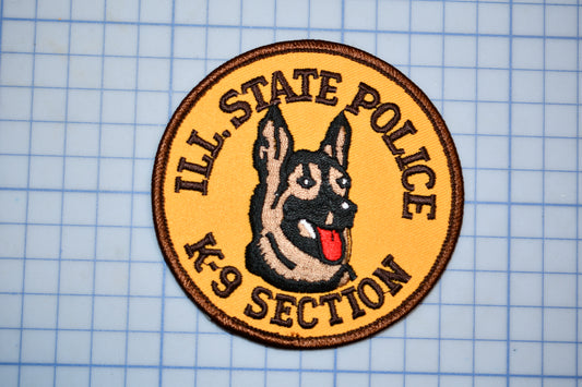 A circular patch with a dog's head and tongue, surrounded by text that reads "ILL. STATE POLICE K-9 SECTION".