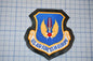 a U.S. Air Force patch with a blue background, yellow wings, and a red circle. The patch is placed on a grid background.