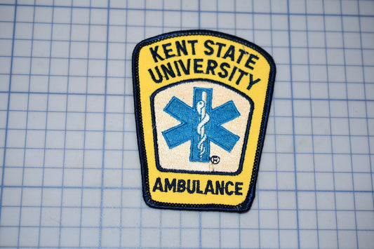 a yellow and blue patch with the text "KENT STATE UNIVERSITY AMBULANCE" and a medical symbol, indicating that it is a patch representing the Kent State University Ambulance Service.