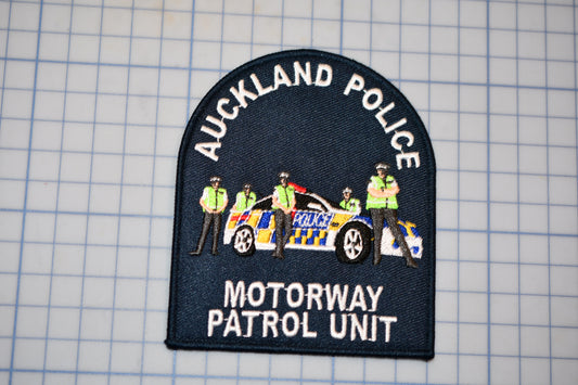 a police patch with a car and several police officers, representing the Auckland Motorway Patrol Unit.