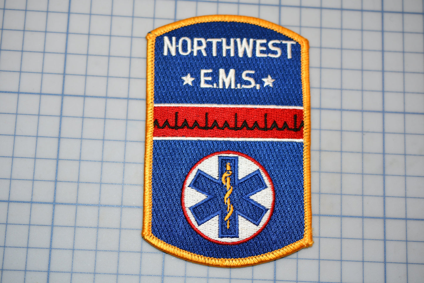 a patch with the text "NORTHWEST EMS" and a medical symbol, likely representing the Northwest Emergency Medical Services (EMS) of the United States.
