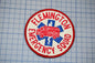 A patch with the text "FLEMINGTON EMERGENCY SQUAD" and an image of a red and blue ambulance, indicating that it is a patch representing the emergency medical services of the town of Flemington.