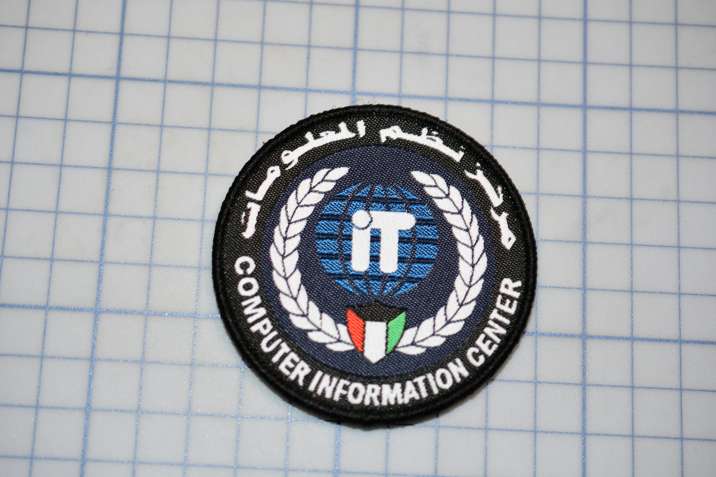 a circular patch with a logo and text, placed on a grid background.