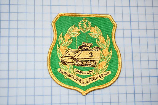 a green and gold patch with a tank on it