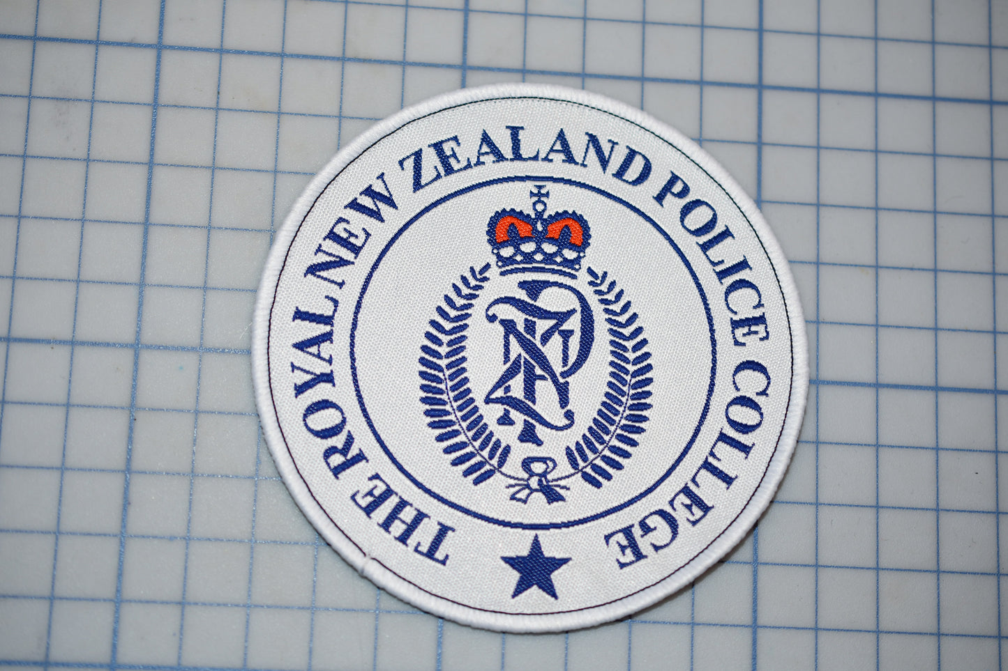 a circular badge with the text "THE ROYAL NEW ZEALAND POLICE COLLEGE" printed on it.