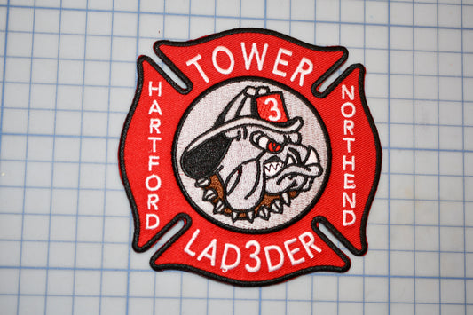 A red and white fire department patch with a bulldog emblem, representing the "Tower 3 Ladder" unit of the North Harvard Fire Department.