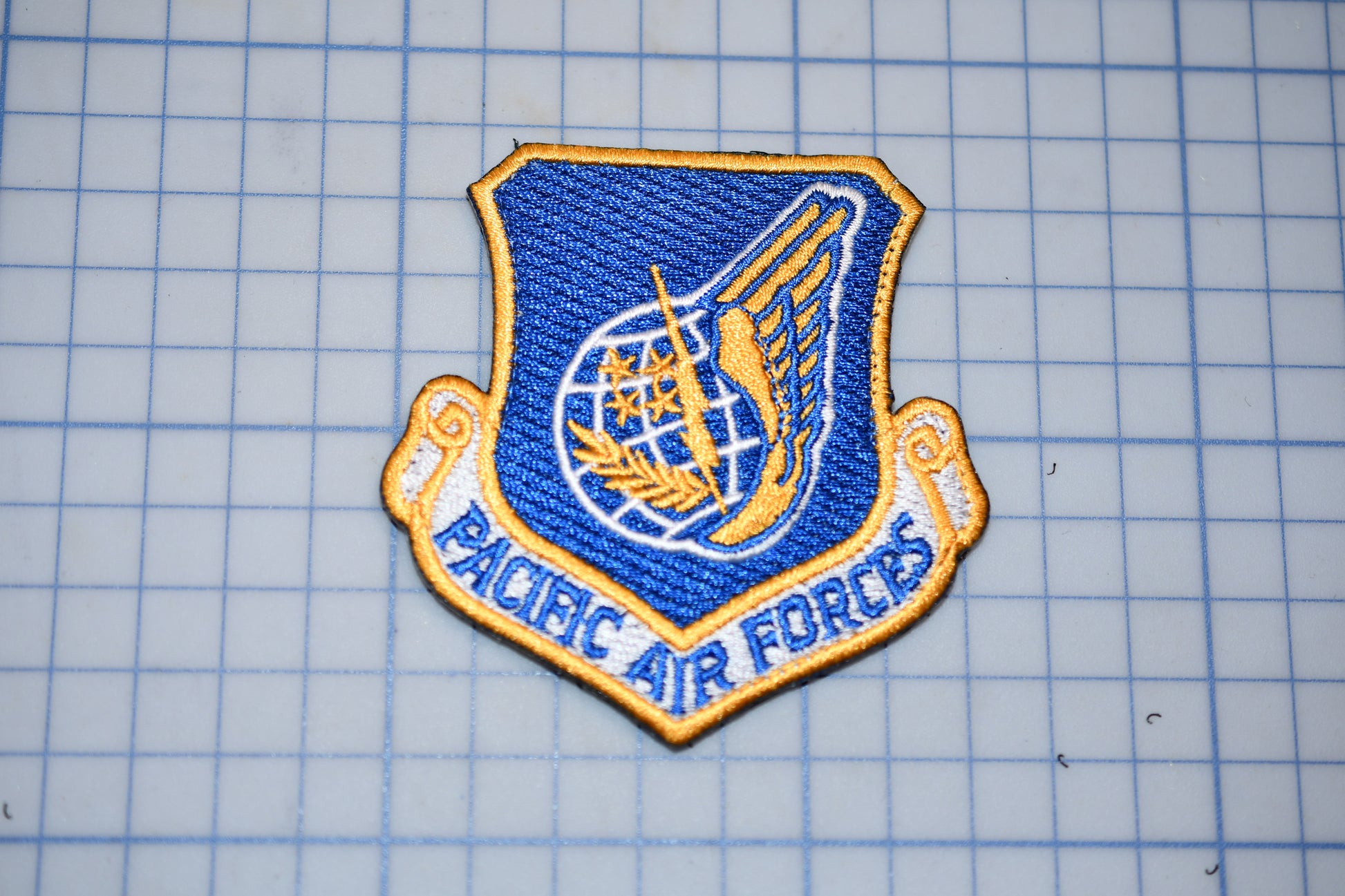 a blue and gold patch with the text "PACIFIC AIR FORCES" on it, which appears to be a military or service insignia.