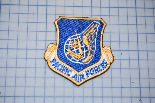 a blue and gold patch with the text "PACIFIC AIR FORCES" on it, which appears to be a military or service insignia.