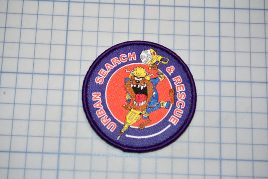 a circular patch with a cartoon character and the text "Search & Rescue" on it, placed on a grid background.