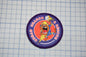 a circular patch with a cartoon character and the text "Search & Rescue" on it, placed on a grid background.