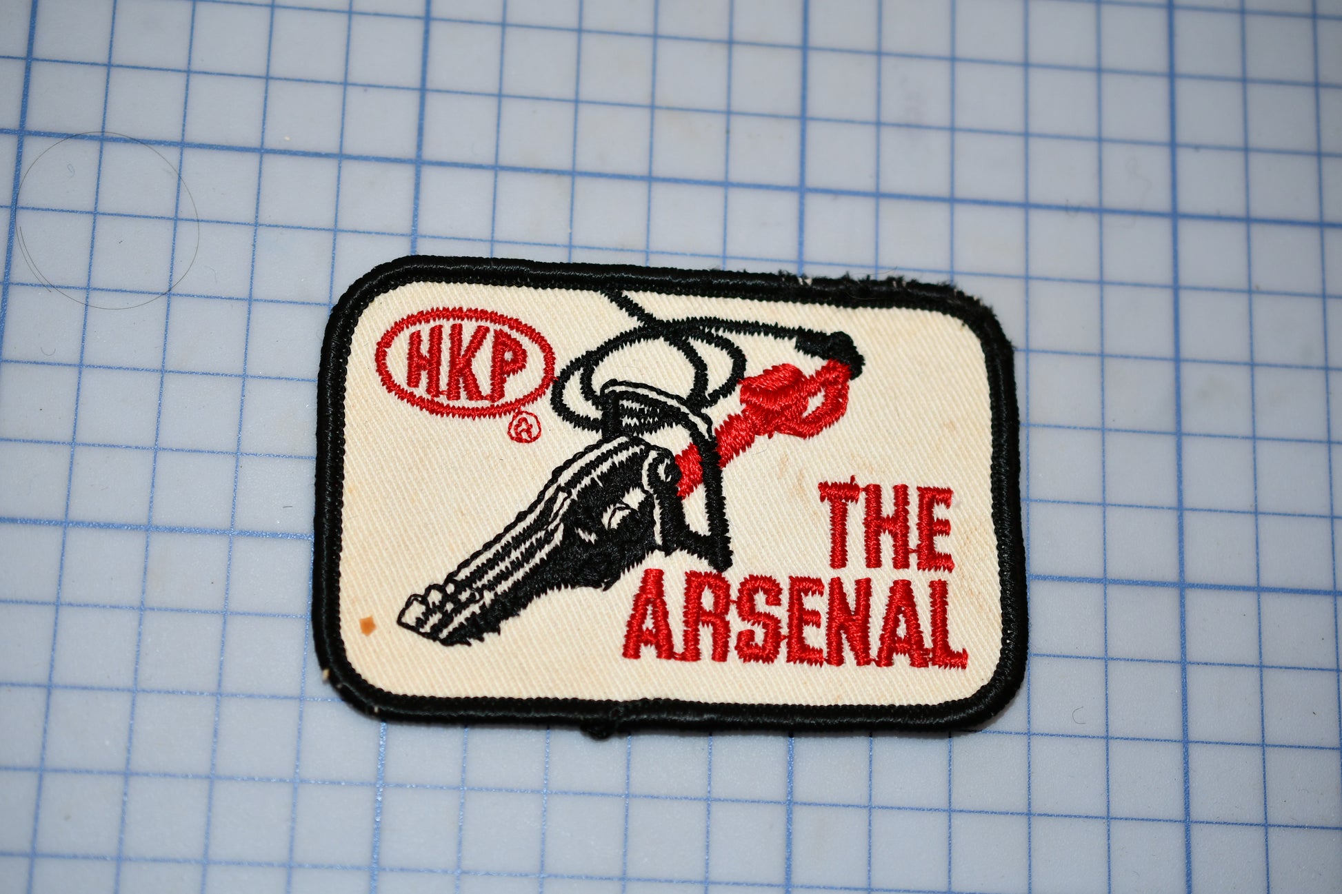 A patch with a key and the text "The Arsenal" printed on it.