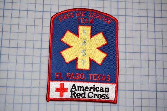 a patch with the text "Fast Aid Service Team" and "El Paso, Texas" written on it, along with a red cross symbol. The patch also displays the text "American Red Cross" at the bottom.