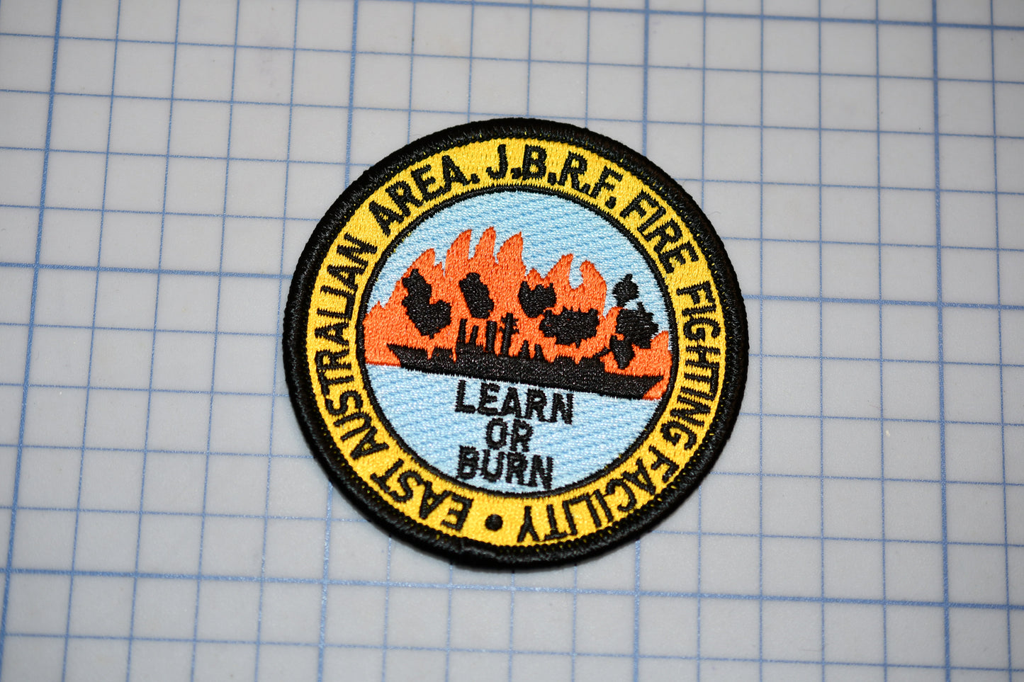 a circular patch with a graphic design and text, placed on a grid background.