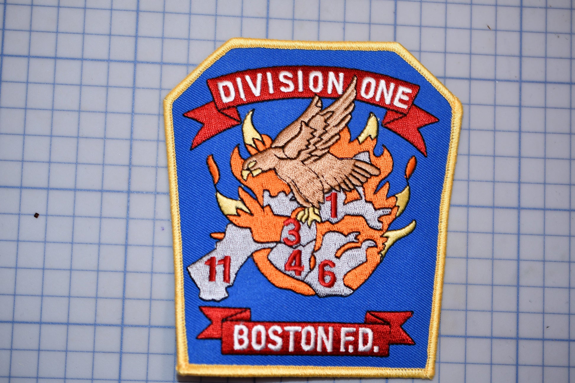 a fire department patch with a bird, flames, and the text "Division One" and "Boston Fire".