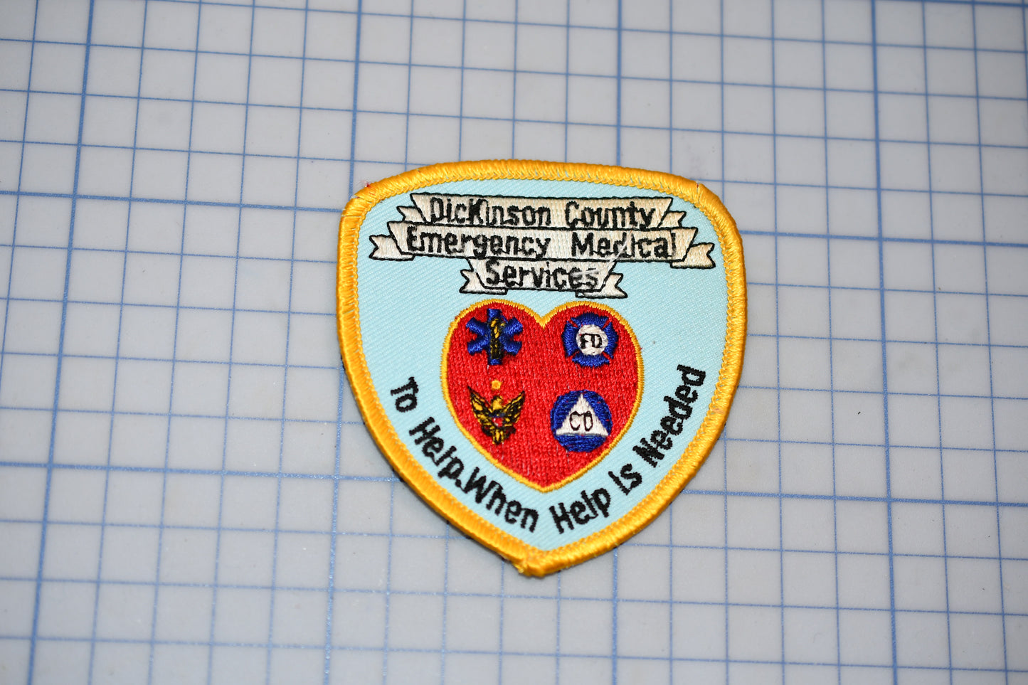 A patch with the text "Dickson County Emergency Medical Services" and "To Help.When Help Is Needed" printed on it, along with various medical symbols and a heart.