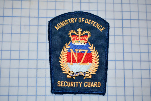 a blue and gold security guard badge with the text "Ministry of Defence Security guard" on it.