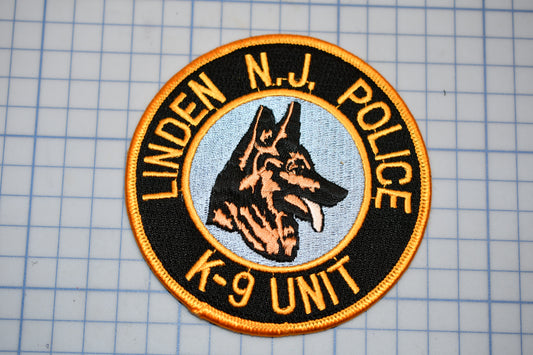 a circular badge or patch with a dog's head and the text "LINDEN NJ POLICE K-9 UNIT" around the edge.
