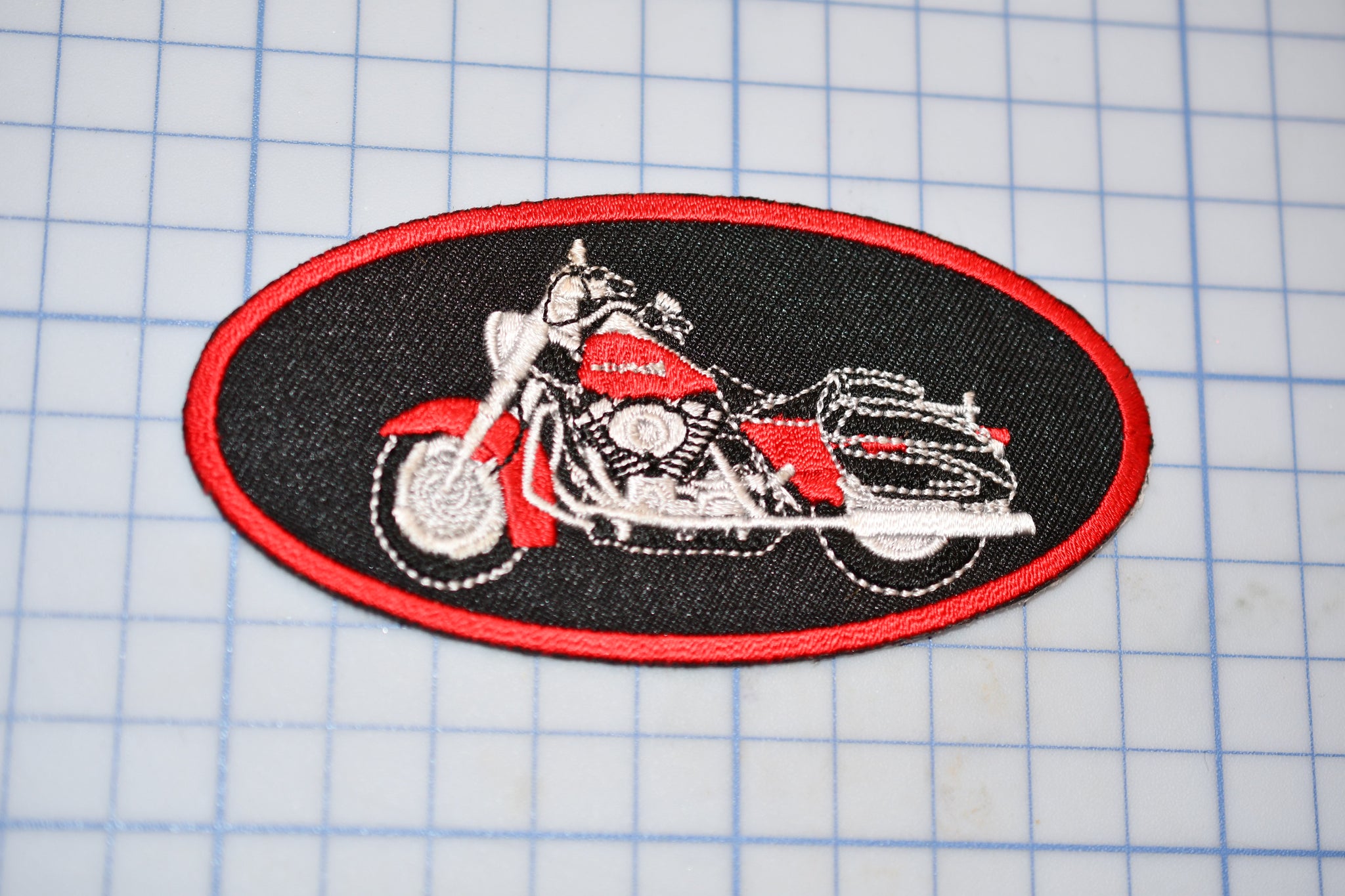 a red and black patch with a picture of a motorcycle