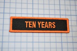 a black and orange patch that says ten years
