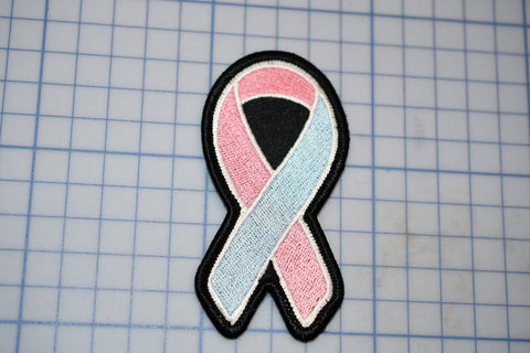 a pink and blue ribbon on a black and white patch